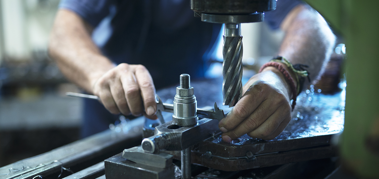 Worker operating industrial machine in metal workshop.